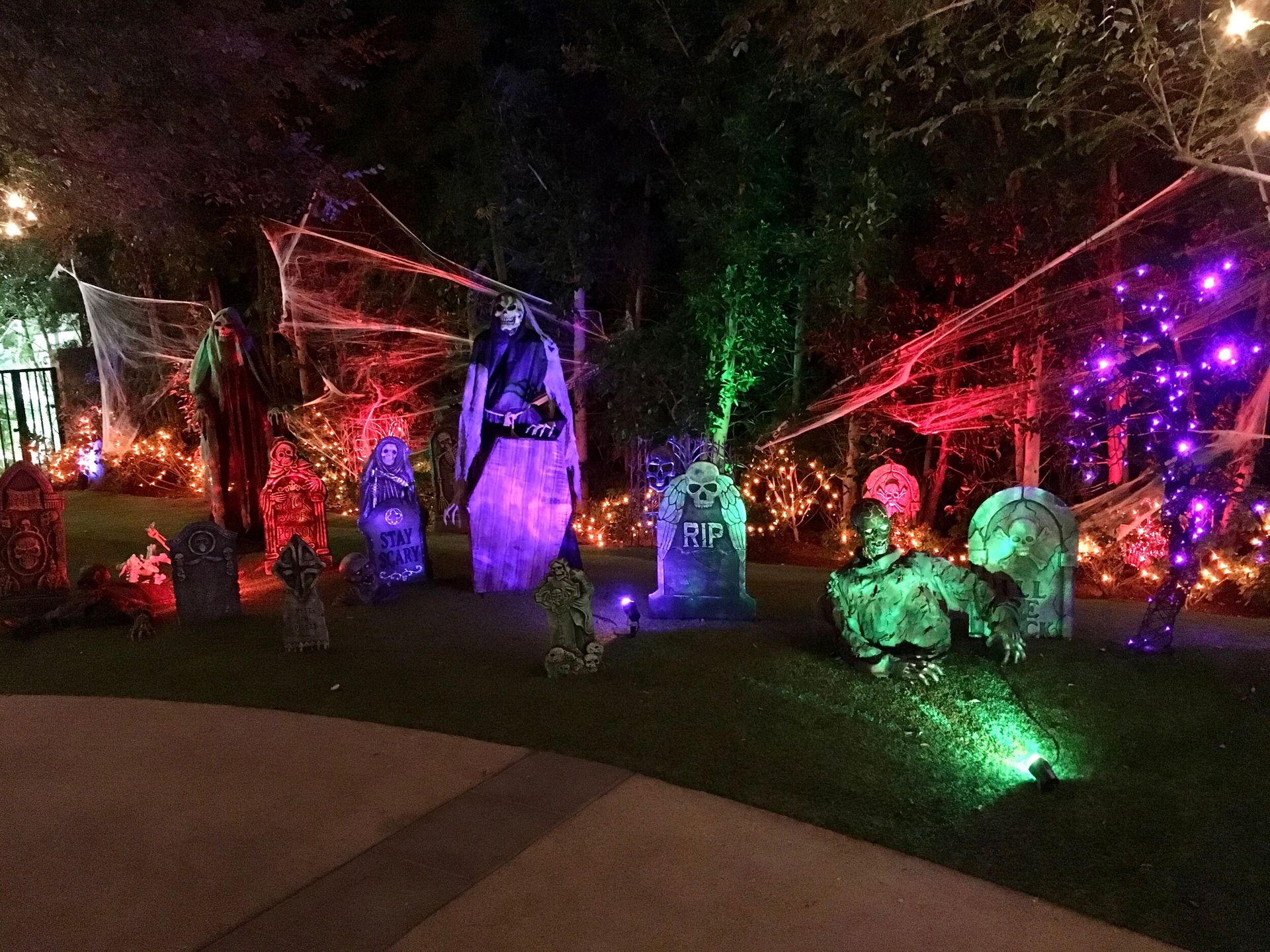 A front-yard graveyard scene lit in purple, green and red